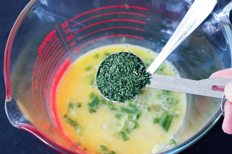 Adding Parsley to Egg and Green Onion Mixture in Glass Measuring Cup.
