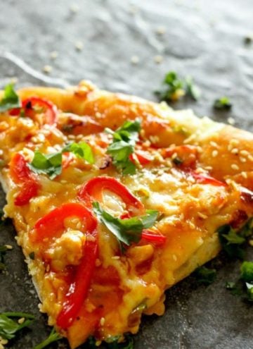 Pizza slice topped with cheese, red peppers and cilantro.