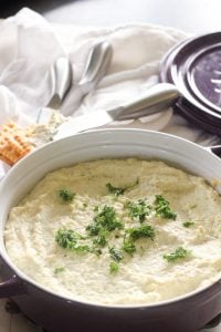 Whipped Artichoke and Feta Dip topped with parsley in purple dish.