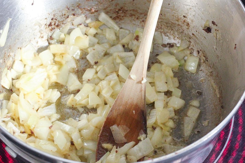Frying onions in butter in metal pot.