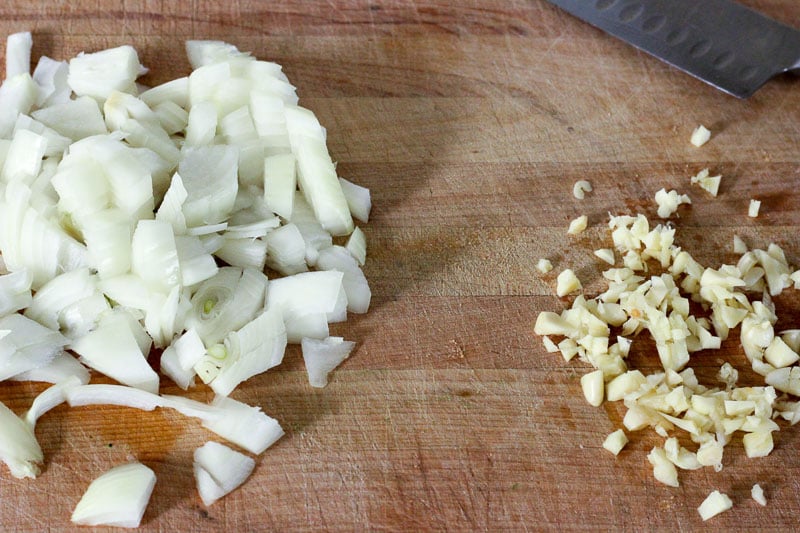 Chopped Onions and Minced Garlic on Wooden Board.