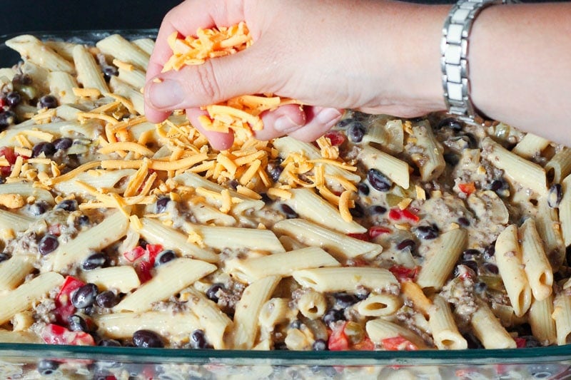 Sprinkling Cheddar Cheese on top of Pasta Dish.