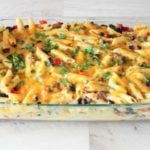Cheesy pasta casserole topped with parsley in glass dish.