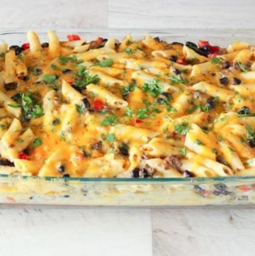 Cheesy pasta casserole topped with parsley in glass dish.