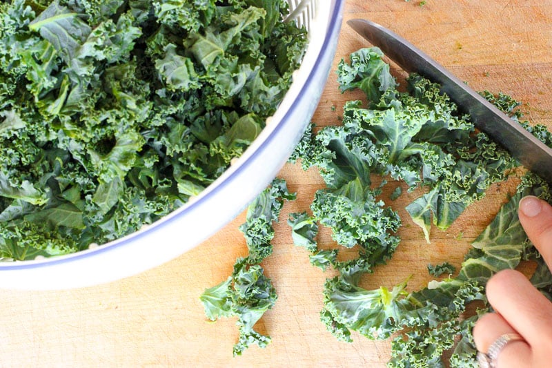 Chopping Kale Leaves and Putting them in White Bowl.