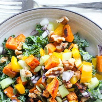 Healthy salad with kale, sweet potato and other vegetables in white bowl.