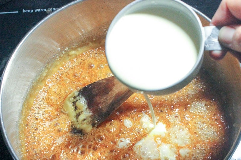 Adding Cream to Boiling Butter and Sugar Mixture in Metal Pot.