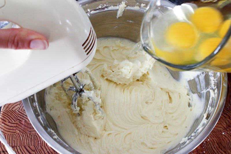 Adding Eggs to Cream Cheese Mixture in Metal Mixing Bowl.