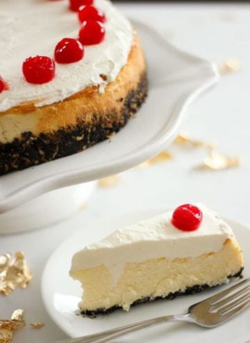 Slice of cheesecake topped with cherry on white plate.