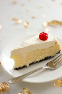 Slice of Chocolate Cherry Coconut Cheesecake Topped with a Cherry on White Plate.