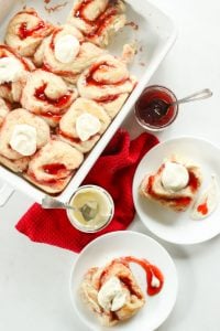 Strawberry Sweet Rolls Topped with Vanilla Cream Cheese Icing in White Plates.