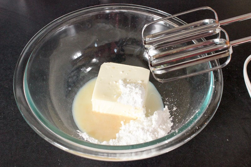 Butter, Milk, Icing Sugar and Vanilla Extract in Glass Mixing Bowl.