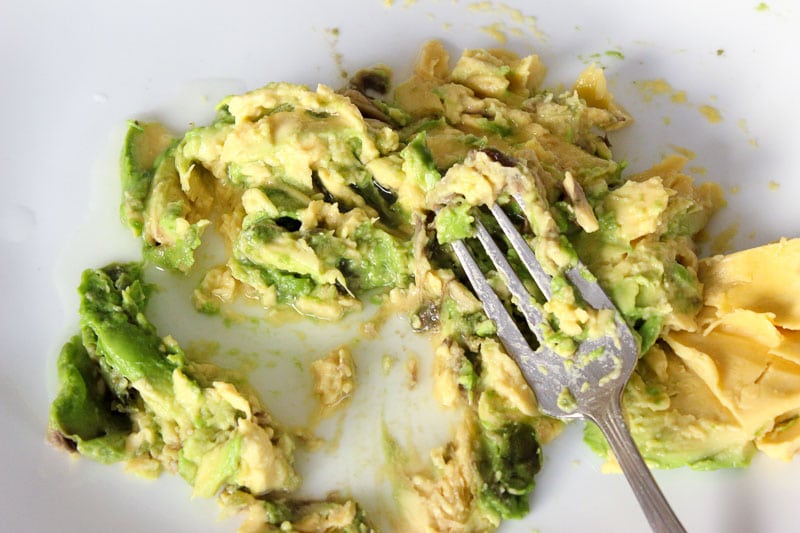Mashing Avocado with Fork in White Plate.