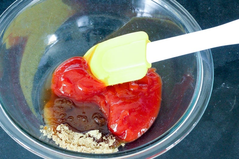 Ketchup and brown sugar mixture in glass mixing bowl.