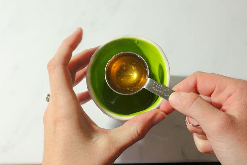 Liquid Honey in Metal Measuring Spoon.