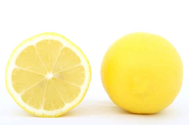 Lemon cut in half with inside showing on white background.