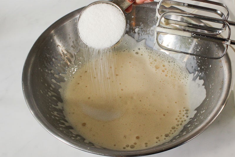 Adding Sugar to Whipped Evaporated Milk in Metal Mixing Bowl.