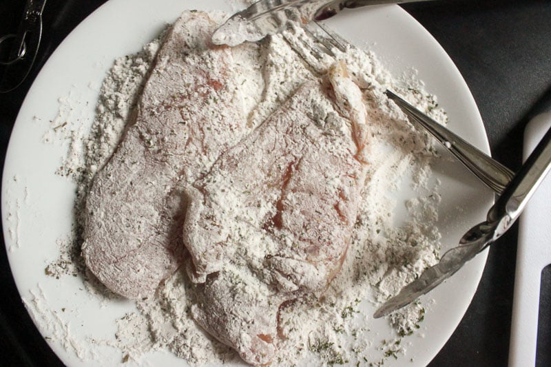 Chicken Dredged in Flour and Herbs on White Plate.