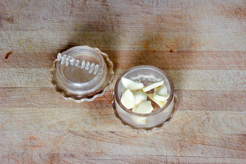 Garlic Cloves in Garlic Press on Wooden Board.
