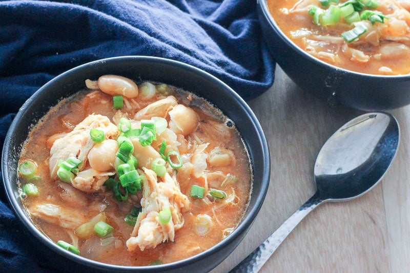 Buffalo Chicken Chili topped with Green Onions in Black Bowls.