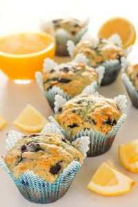 Lemon Blueberry Muffins in Blue Wrappers next to Lemon Wedges.