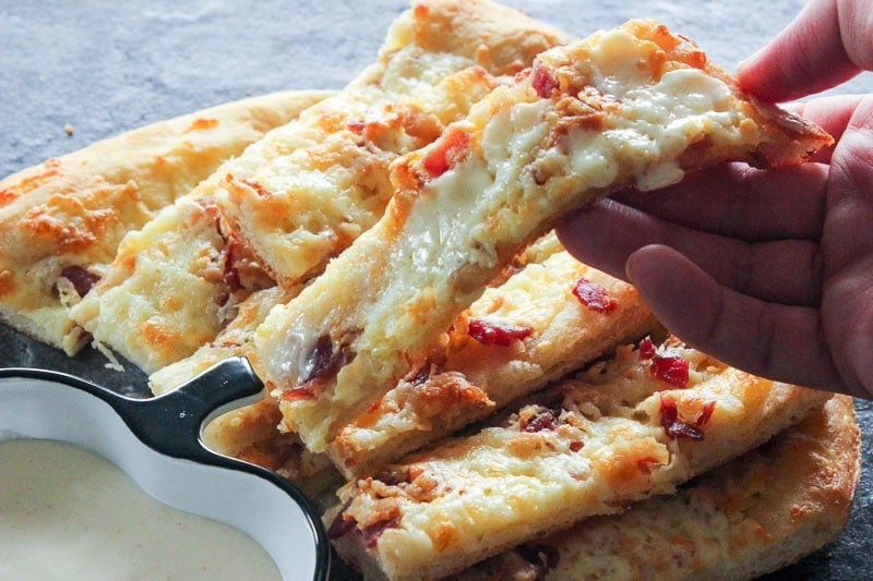 Stack of Garlic Fingers topped with Bacon and Melted Mozzarella Cheese.