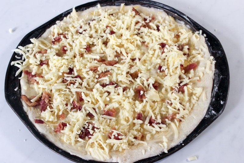 Bacon and Shredded Mozzarella Cheese on Pizza Dough in Round Pizza Pan.
