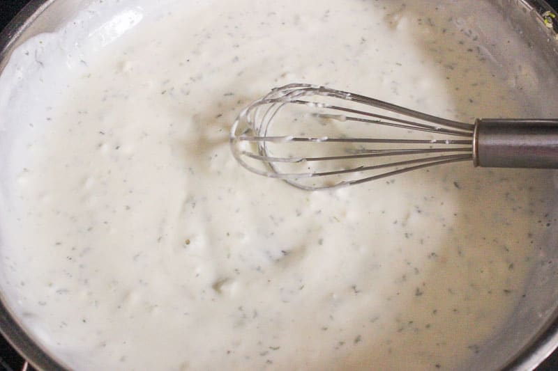 Mixing Creamy garlic sauce in Frying Pan with Whisk.