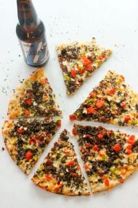 Sliced Bacon Cheeseburger Pizza and bottle of beer on white background.