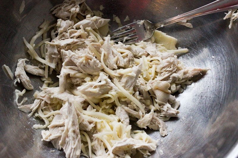 Mixing Shredded Chicken with Shredded Mozzarella Cheese in Metal Bowl.