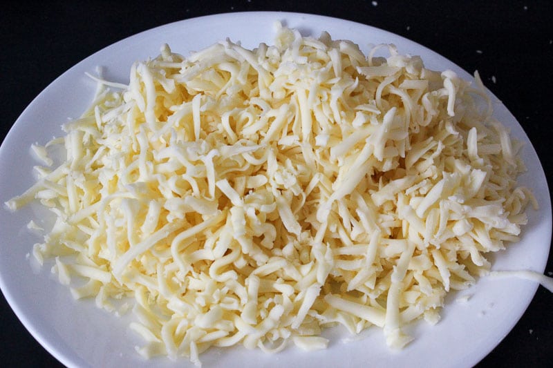 Shredded mozzarella cheese on a white plate.