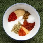 Small bowl full of colourful herbs and spices on a green cloth.