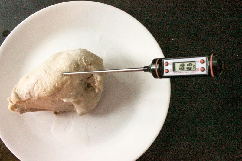 Testing Internal Temperature of Chicken With Meat Thermometer on White Plate.