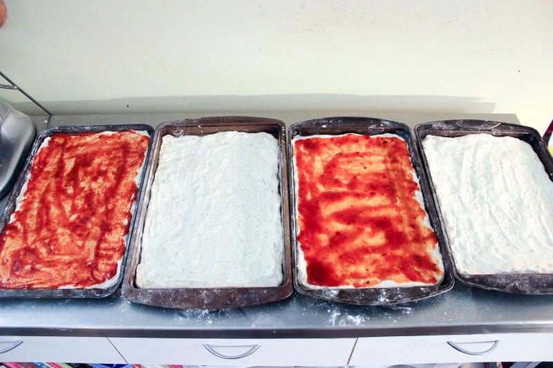 Spreading Pizza Sauce on Pizza Dough in Rectangular Sheet Pans.