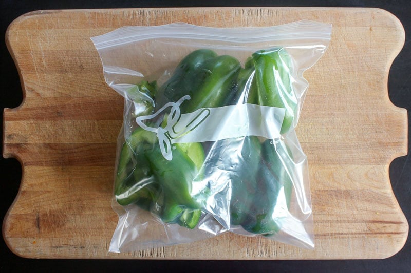 Halved Green Peppers in Resealable Plastic Bag on Wooden Board.