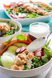 Salad bowls with lettuce, cucumber, radish, carrots, peas and a creamy herb dressing.