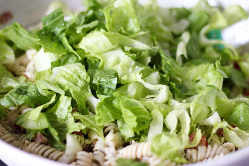 Mixing lettuce into BLT pasta salad.