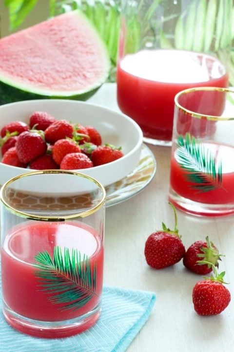 Red juice, with strawberries and watermelon in the background.