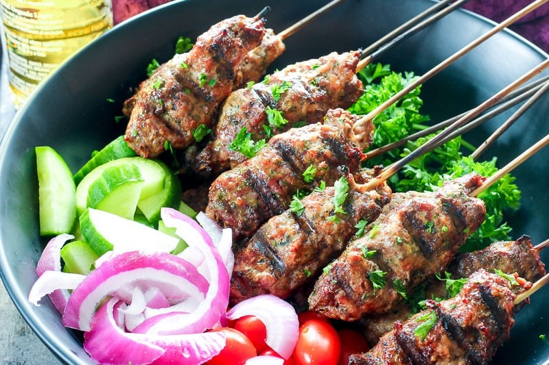 Platter of beef kebabs, cucumber, red onions and grape tomatoes.