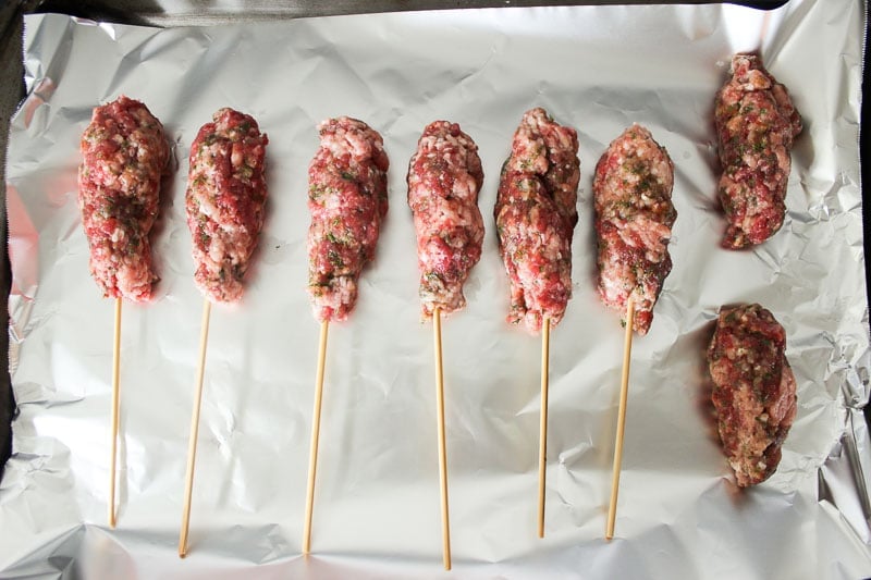Uncooked Beef Kebabs Lined on Aluminum Foil.