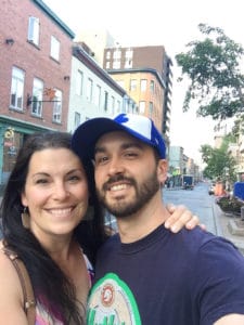 Woman and man taking a picture in front of buildings.