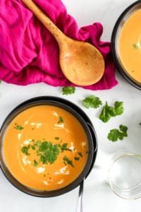 Thai Carrot and Squash Soup topped with Cilantro and Coconut Milk in Black Bowl.