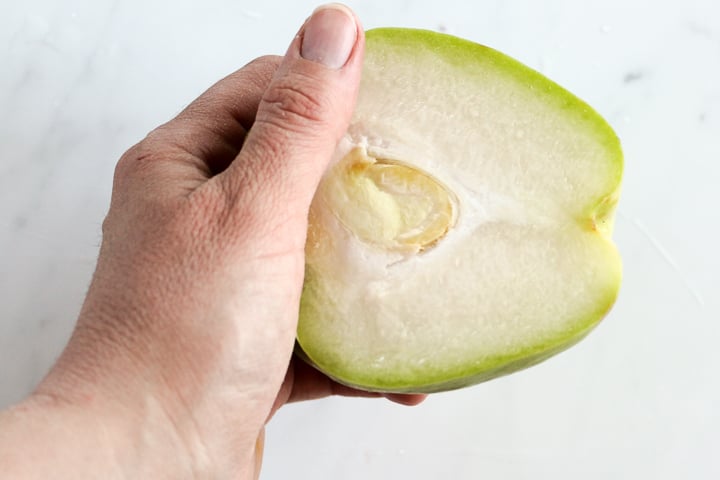 Hand holding half a chayote squash