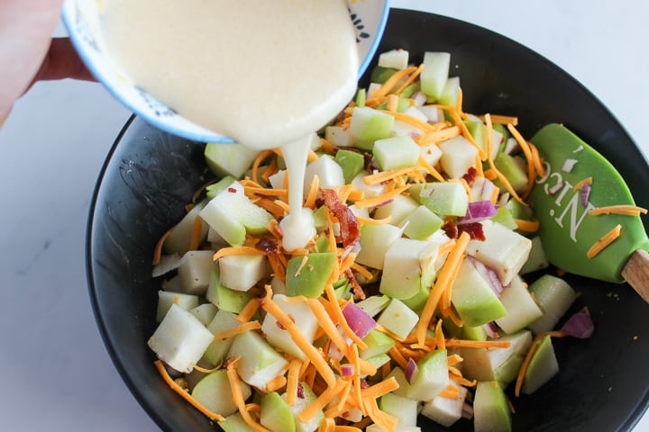 Pouring dressing into bowl of chayote squash salad ingredients