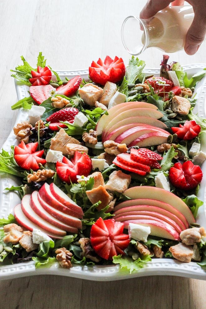 Platter of Strawberry Chicken Salad with dressing being poured on