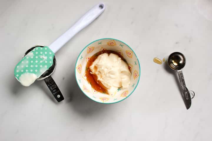 Bowl with mayonnaise and maple syrup in it, with spatula and measuring tools