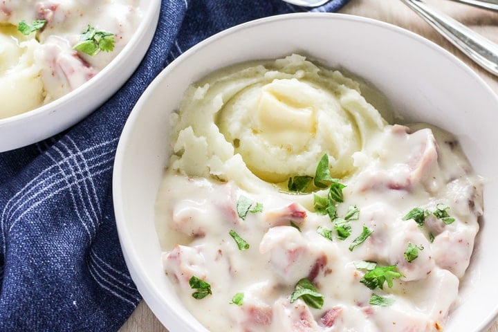 Bowl of ham in white sauce, served over potatoes