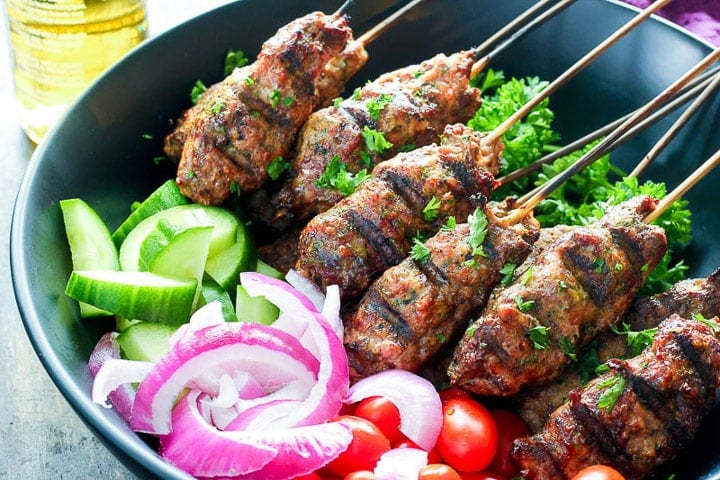 Beef kebabs in bowl with cucumber, red onion and tomato