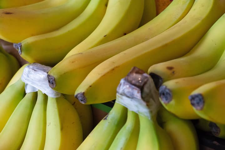 Many bunches of bananas with tops wrapped in plastic to last longer