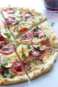 Thin crust pizza with salami, blue cheese, apple and parsley.